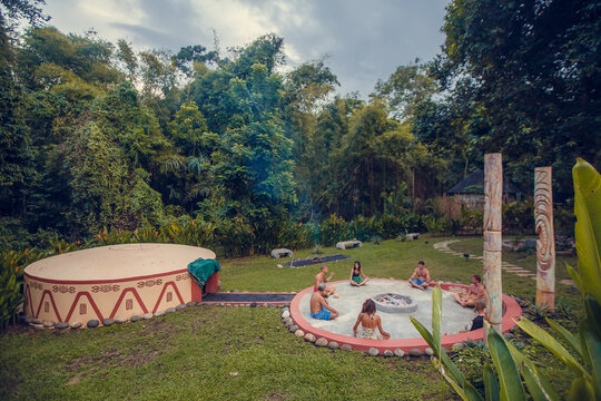 Group of people preparing for Mayan Temazcal- traditional steam sauna bath of Mesoamerican cultures. Diverse multiethnic friends sitting on grass and taking training course before Temazcal experience