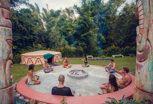 Group of people preparing for Mayan Temazcal- traditional steam sauna bath of Mesoamerican cultures. Diverse multiethnic friends sitting on grass and taking training course before Temazcal experience