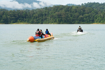 Fototapeta na wymiar People enjoying water activities on banana boat at the Kenyir Lake, Terengganu, Malaysia.