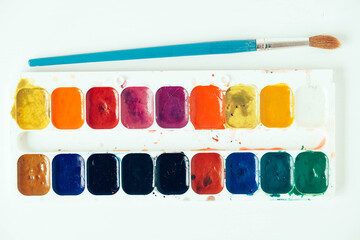 Set of watercolor paints and brushes for painting on a white background. Top view. Copy, empty space for text