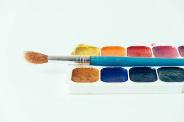 Set of watercolor paints and brushes for painting on a white background. Top view. Copy, empty...