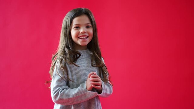 Young casually dressed girl jumps into empty frame from bottom of screen against red studio background smiling and laughing at camera - shot in slow motion
