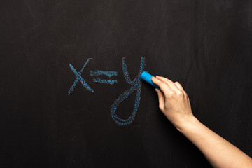 formula equation x = y is written in chalk on a black slate board.