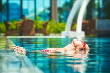 Fotobehang Beautiful young woman relaxing in the luxury swimming pool. Summer luxury vacation during summer holiday © soft_light