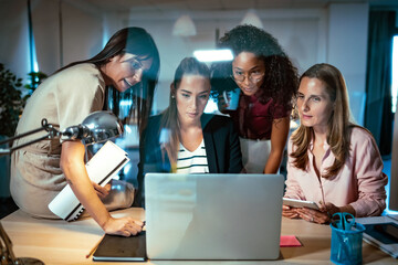 Four smart businesswomen talking and reviewing the latest work done on the computer in a joint...