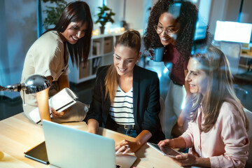 Four smart businesswomen talking and reviewing the latest work done on the computer in a joint workspace.