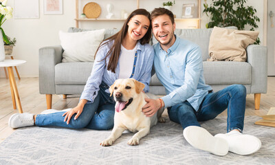 Young happy spouses with dog sitting in living room