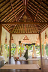 Fit young couple doing acro yoga Front Plank or Airplane Pose ourdoors. Man lying on floor and balancing woman in his feet. Healthy lifestyle and wellness