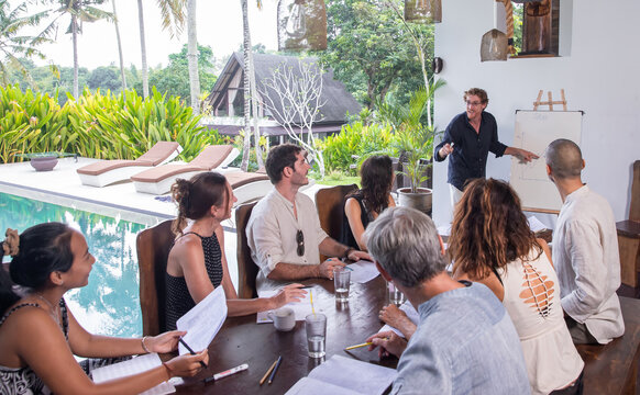 Diverse group of multiethnic people having business meeting, seminar, presentation outdoor in tropical conference. Team members listening attentively to a cheerful sharp speaker holding a presentation