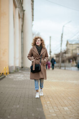Portrait of a curly-haired young woman who walks the streets of the city
