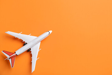 Toy airplane on orange background, top view. Space for text