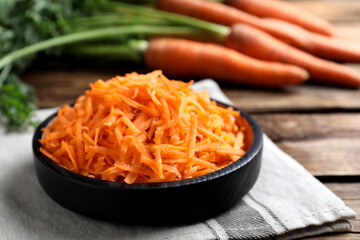 Grated carrot in plate on wooden table