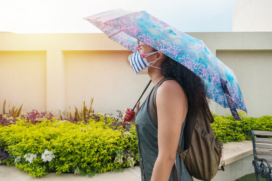 Athletic Woman With Face Mask And Umbrella Walking In The Park