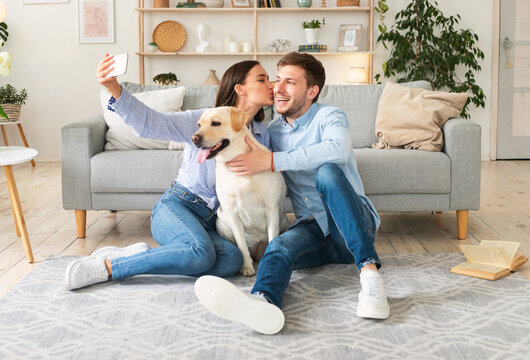 Young couple taking selfie with their dog in living room
