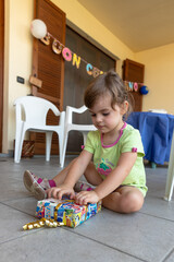 Cute smiling little girl happily opening gift box