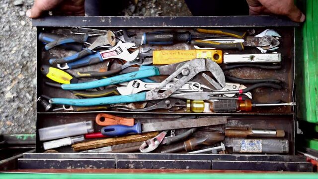 Adult Caucasian male hands pulls open and closes toolbox looking for wrench, directly above static close up 