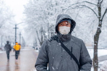 Fototapeta na wymiar Portrait of a man wearing a medical protective mask on his face in winter, Covid-19 coronavirus pandemic, virus protection