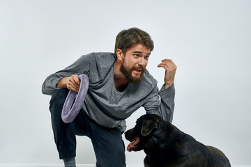 Man with dog training gray ring doing exercises pets light background.