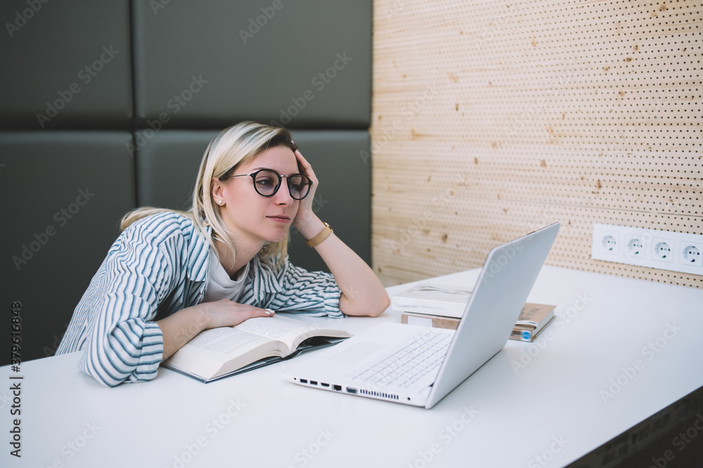 Poster caucasian female student reading information for course work tired from exam preparation in universi