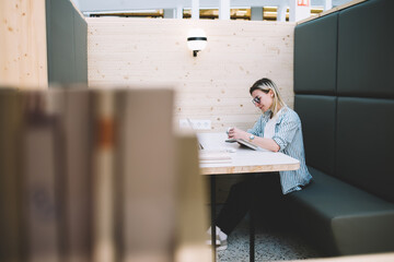 Caucasian female in glasses reading information using modern technology on distance work, youthful...