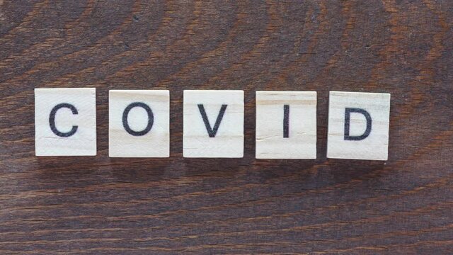 stop motion animation with lettering "COVID", light wooden letters on a dark wooden background
