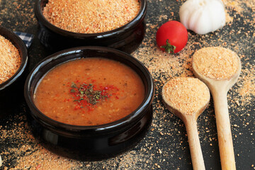 Traditional Turkish Homemade Dry Soup,Tarhana grains and cooked in casserole bowl on black surface with ingredients