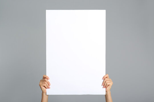 Woman Holding White Blank Poster On Grey Background, Closeup. Mockup For Design