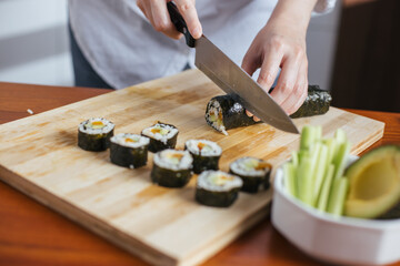 Female chef cutting sushi in the kitchen