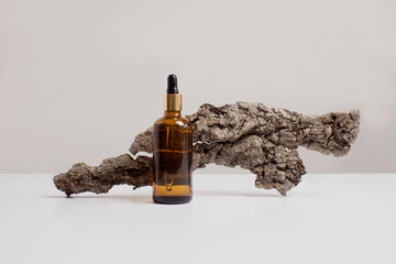 Serum, oil, acid, lotion in brown dropper glass and tree bark in front of beige background side view with copy space. Spa product composition. Organic, bio, natural cosmetic. Beauty, skincare concept.