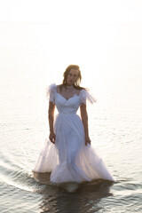 Fototapeta na wymiar Female in wedding dress walking in water. High quality photo