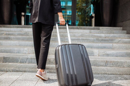 Close up of a young business woman walking up the staircase with a suit ready to check in at hotel's reception. Beginning of a business trip for a professional worker. Work and travel concept.