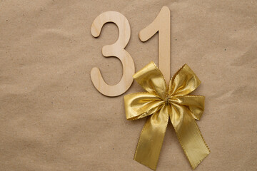 Light wooden numerals 31 lie on craft paper with a gold bow