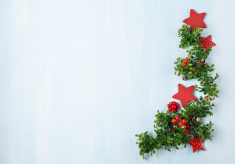 Christmas composition with fir branches, red berries, eco friendly decorations on blue wooden background.