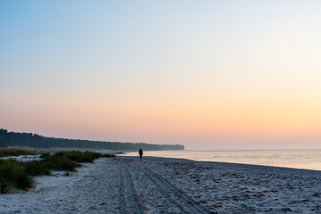 Fototapeta na wymiar sunrise over the sea with a beach walker