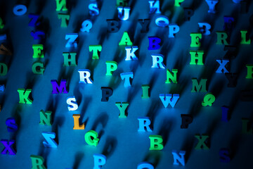 Multicolored letters of the alphabet. Chaotic English letters cast a shadow. Volumetric symbols on a blue background. Letters as a symbol of reading. Concept - reading English books and literature