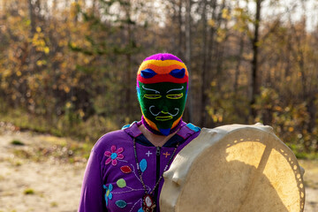 Shaman with a tambourine in a colored mask on his face.