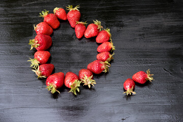 Frische Erdbeeren in einer Herzdarstellung auf einem schwarzen Hintergrund