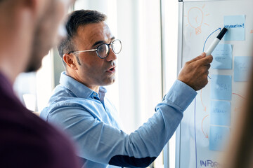 Elegant mature businessman explaining a project to his colleagues on coworking place.