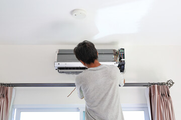 Technician preparing to installs new air conditioner on white wall in the room.