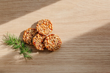 Christmas composition. Kozinak cookies from seeds and nuts, spruce branch on a wooden background. Flat lay, top view, copy space