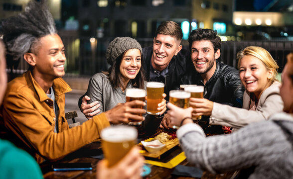 Happy friends group drinking beer at brewery bar out doors - Friendship lifestyle concept with young people enjoying time together at open air pub - Selective focus on girl with hat