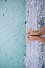 Slim female tanned legs on wooden pier near sea