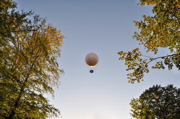 Balloon flight against the blue sky on a summer evening framed by trees.