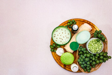 Natural spa accessories and green grapes placed on a wooden plate