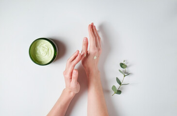 Revitalizing hand cream for healing and recovery after excessive use of soap and disinfectants. Young woman applying moisturizing lotion. Copy space, close up, pink background, flat lay, top view.