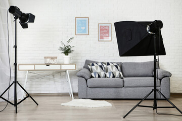 Photo studio with professional equipment and home interior on brick wall background