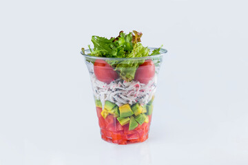 Fresh Tartar with Snow crab meat, avocado and tomato pieces inside plastic delivery glass. served with salad mix isolated on gray background. European cuisine. Restaurant menu dish isolation  