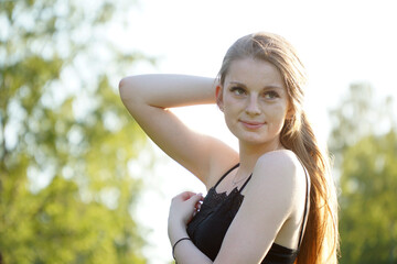 Hübsche junge Frau lächelt freundlich an einem sonnigen Sommertag im Park