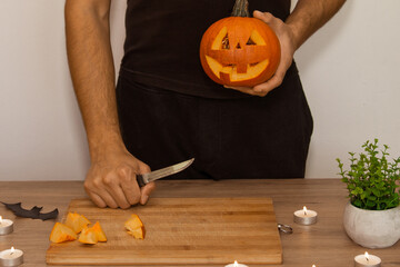 A man carves eyes and a mouth in a pumpkin for Halloween.