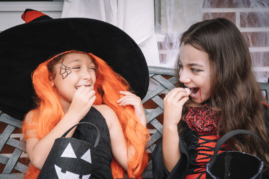 Two Small Girls In Costumes Celebrate Halloween By Eating Candy